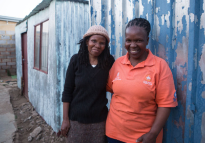 Social worker and mother standing outside small house in South Africa